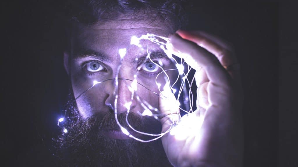 Man Holding String of Lights in Front of His Face