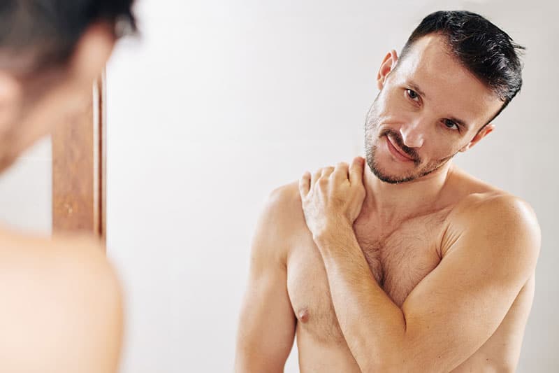 Man looking in mirror after infrared sauna therapy